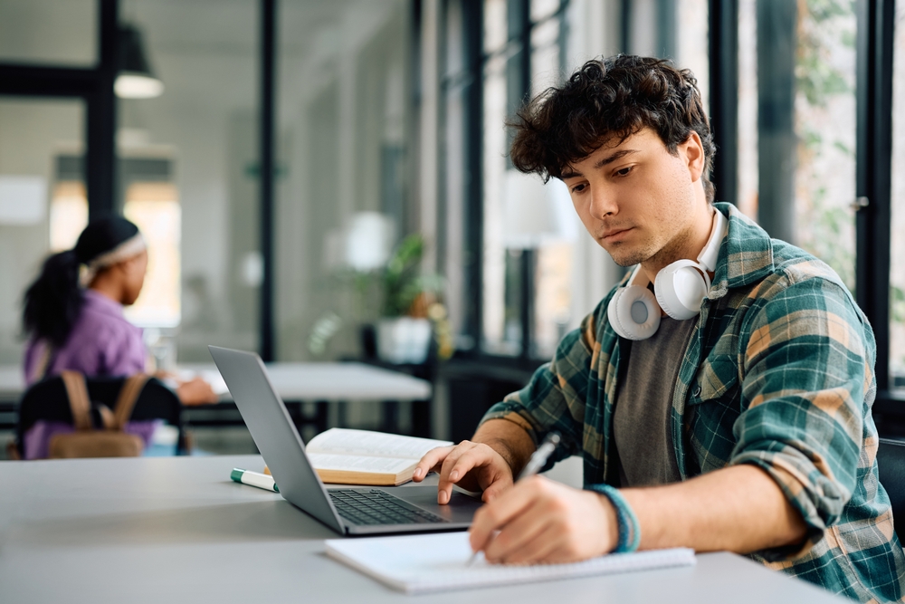 university,student,writing,while,using,laptop,and,studying,in,the